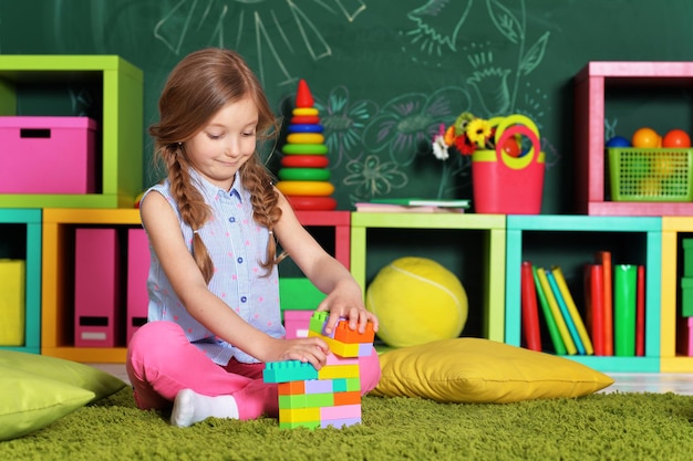 Adorabile bambina che gioca con blocchi di plastica colorati