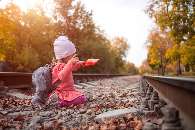 Adorabile bambina che gioca con una paletta sui binari