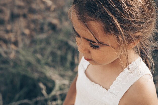 Adorabile bambina che gioca in un campo di mais in una bella giornata autunnale. Bambino grazioso che tiene una pannocchia di mais. Raccolta con i bambini. Attività autunnali per bambini.