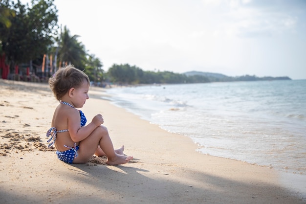 Adorabile bambina che gioca sulla spiaggia sabbiosa delle vacanze estive dell'isola tropicale