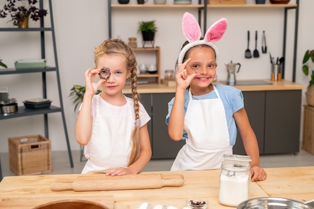 Adorabile bambina che indossa un grembiule in piedi al tavolo mentre è avvolta nel fare una sorpresa per il compleanno di suo padre.