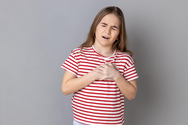 Adorabile bambina che si tiene per mano sul petto sentendo dolore rischio di infarto