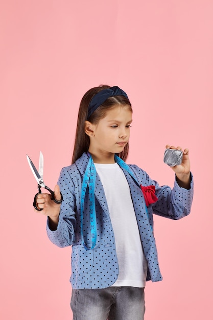 Adorabile bambina che tiene metro a nastro e rocchetto di filo