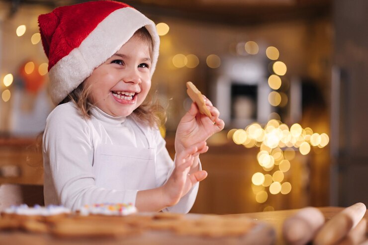Adorabile bambina con il cappello di Babbo Natale che mangia pan di zenzero fatto in casa e ride un ragazzino felice
