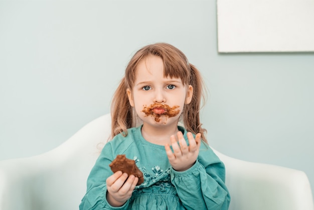 Adorabile bambina con il viso ricoperto di cioccolato.