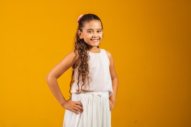 Adorabile bambina con lunghi capelli ondulati che sorride alla telecamera felice