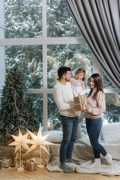 Adorabile bambina con mamma e papà si divertono a Natale in famiglia alla moda a casa