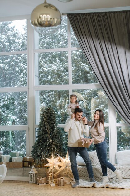 Adorabile bambina con mamma e papà si divertono a Natale in famiglia alla moda a casa