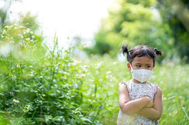 Adorabile bambina con maschera protettiva in piedi sul campo