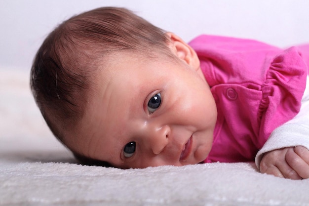 Adorabile bambina di un mese in abito rosa giace su una morbida coperta