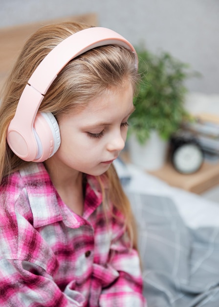 Adorabile bambina in cuffia si diverte con una musica.