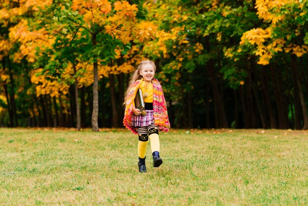 Adorabile bambina in un bellissimo parco autunnale