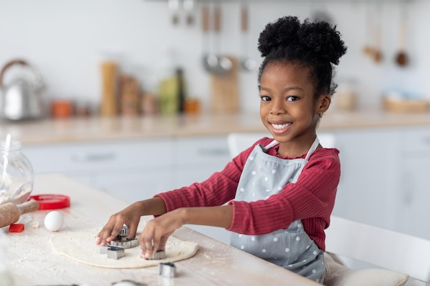 Adorabile bambina nera che prepara i biscotti per la sua famiglia