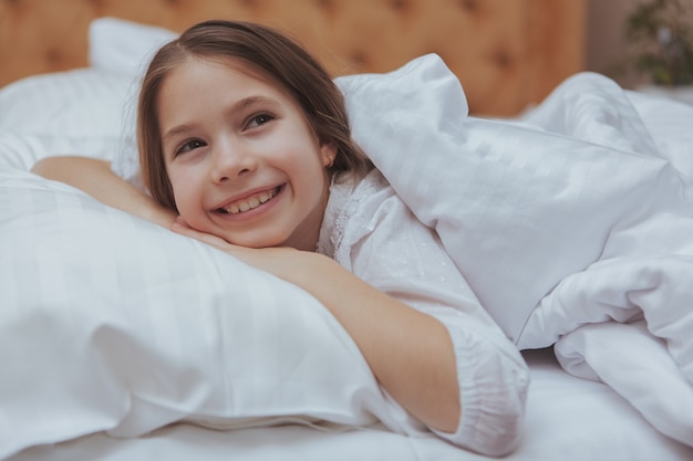 Adorabile bambina sdraiata a letto a casa