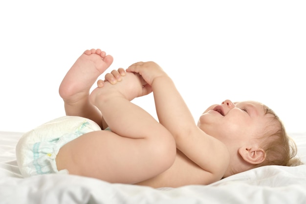 Adorabile bambina sdraiata in coccole su una coperta su uno sfondo bianco