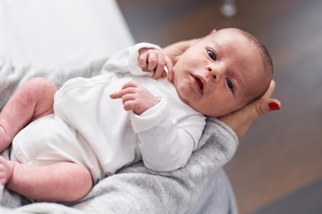 Adorabile bambino caucasico sulle braccia della madre a casa