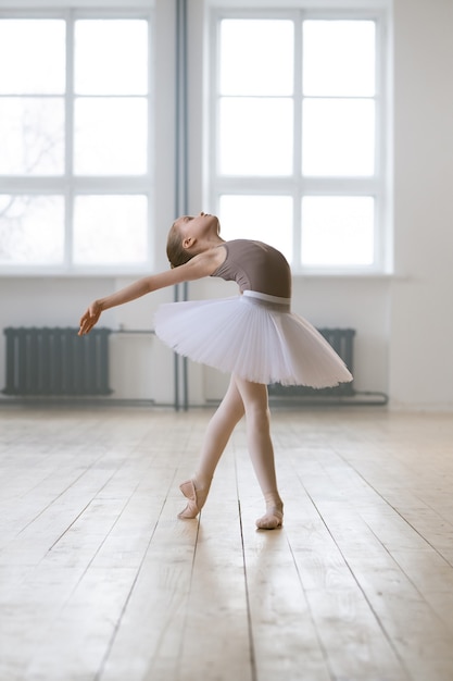 Adorabile bambino che balla il balletto classico in uno studio bianco