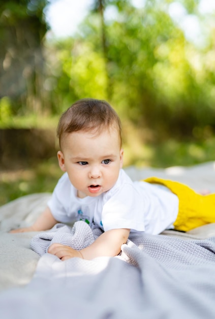 Adorabile bambino che gioca su una coperta in erba verde Divertimento all'aria aperta per i bambini