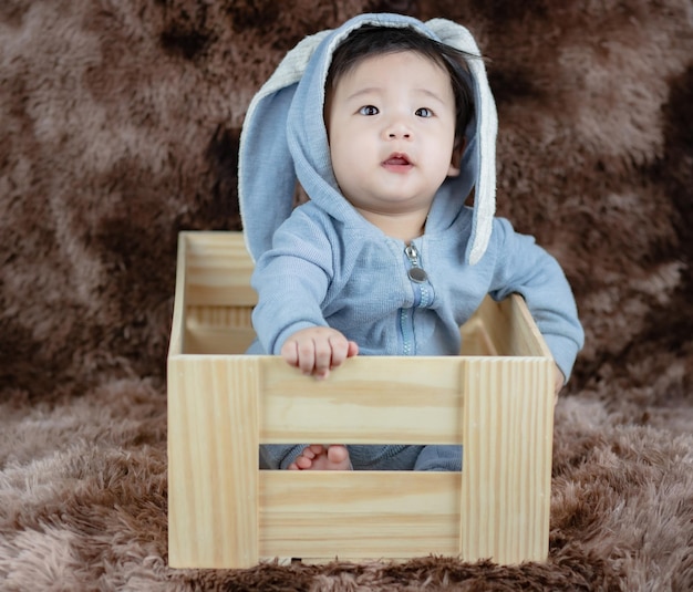 adorabile bambino che indossa un costume da coniglio su una scatola di legno
