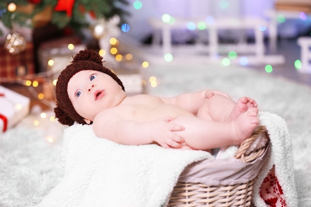 Adorabile bambino con cappello lavorato a maglia marrone in cestino di vimini decorato