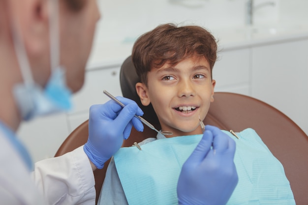 Adorabile bambino felice che sorride con i denti sani, ottenendo il suo esame dentale