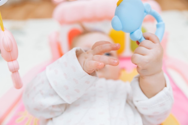 Adorabile bambino sdraiato su un colorato tappeto da gioco per bambini con giocattoli Spazio per lo sviluppo iniziale e l'attività del bambino bambino 6 mesi