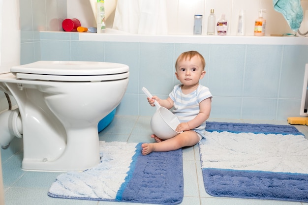 Adorabile bambino seduto sul pavimento in bagno