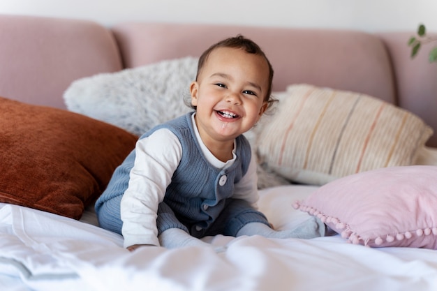 Adorabile bambino sorridente e seduto sul letto