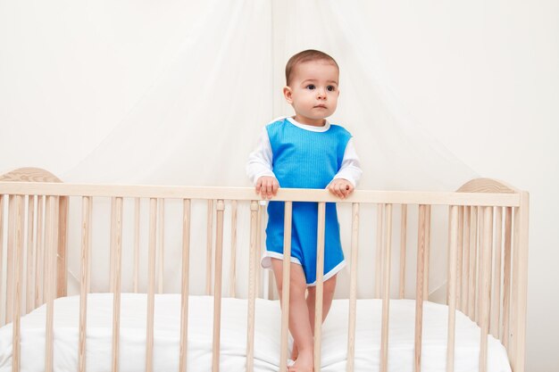 Adorabile bel bambino nel letto guarda da un lato su sfondo bianco