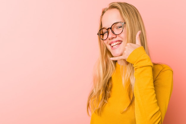 Adorabile donna adolescente che mostra un gesto di chiamata di telefonia mobile con le dita.