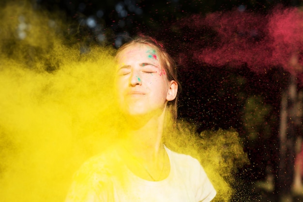 Adorabile donna bionda in colori vibranti che esplodono intorno a lei alla celebrazione di Holi