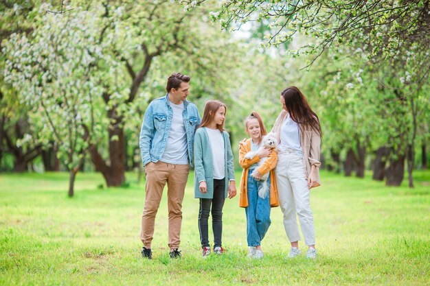 Adorabile famiglia nel giardino di ciliegio in fiore in una bella giornata di primavera