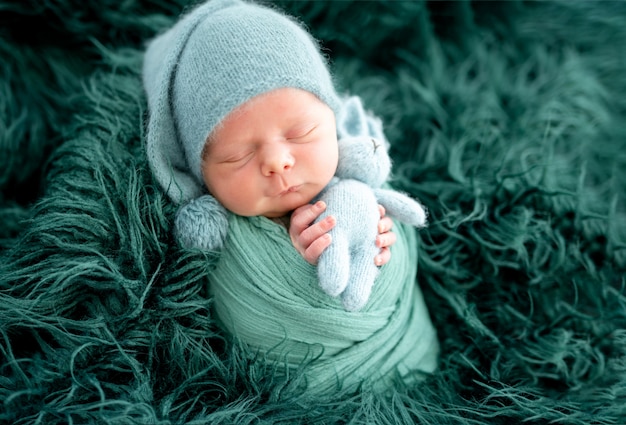 Adorabile neonato in cappello verde lavorato a maglia