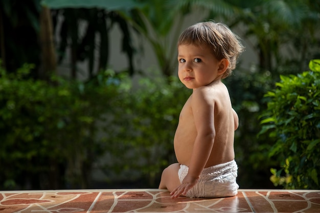 Adorabile piccolo bambino seduto all'aperto giornata di sole estivo