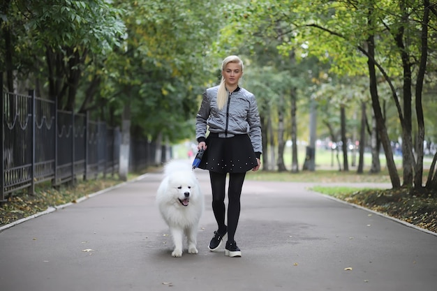 Adorabile ragazza a passeggio con un bellissimo cane soffice Samoiedo