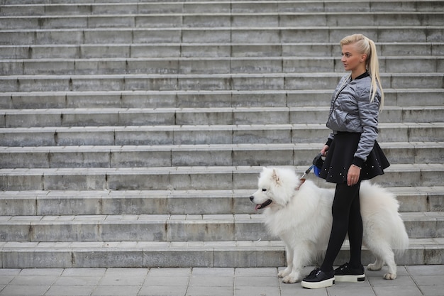 Adorabile ragazza a passeggio con un bellissimo cane soffice Samoiedo