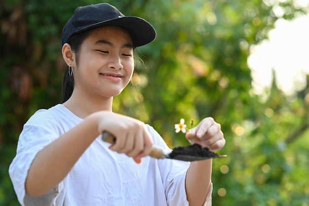 Adorabile ragazza con pala da giardino con piante verdi piantina in mano Giornata della Terra Concetto di ecologia