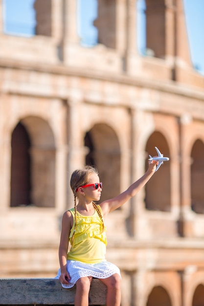 Adorabile ragazza con piccolo giocattolo modello aereo sfondo Colosseo a Roma, Italia