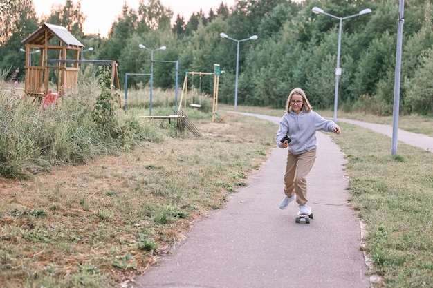 Adorabile ragazza felice che guida skateboard nel parco