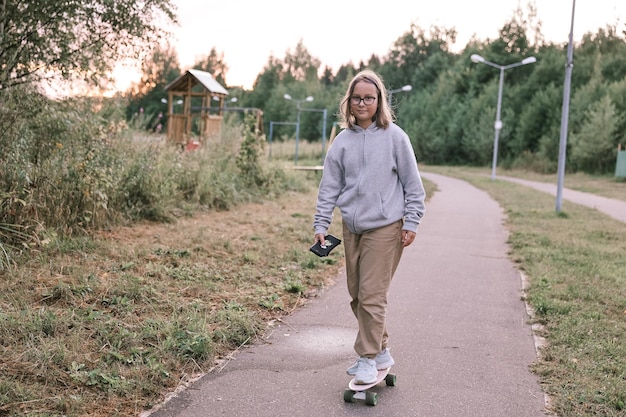 Adorabile ragazza felice che guida skateboard nel parco