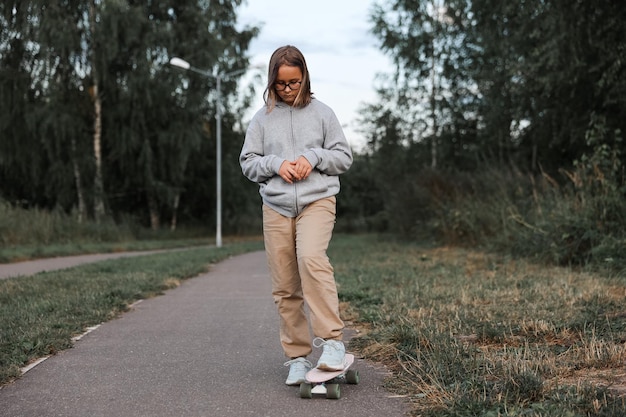 Adorabile ragazza felice che guida skateboard nel parco