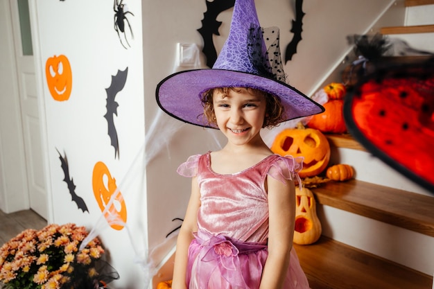 Adorabile ragazza in posa in abito rosa e cappello da strega