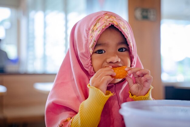 adorabile ragazza musulmana mentre si siede e mangia nella sala da pranzo