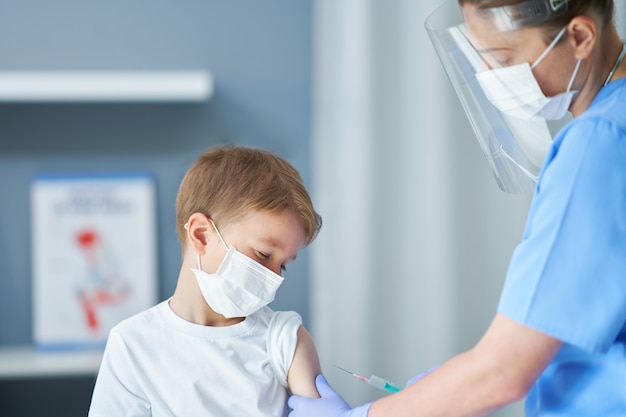 adorabile ragazzino che viene vaccinato nell'ufficio del medico