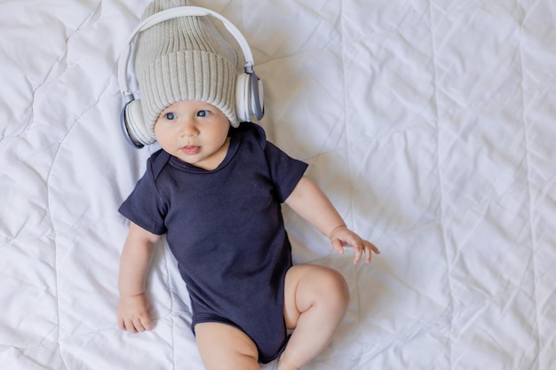 Adorabile ragazzino con cappello con le cuffie posate su coperta, carta, spazio per testo, banner