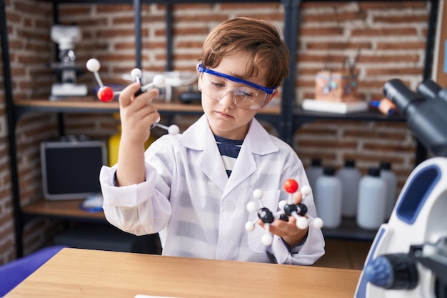 Adorabile studente ragazzo ispanico che tiene molecole in aula di laboratorio