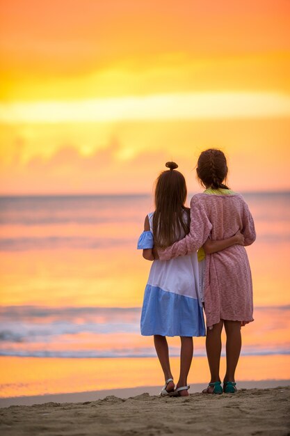 Adorabili bambine sulla spiaggia con bel tramonto colorato