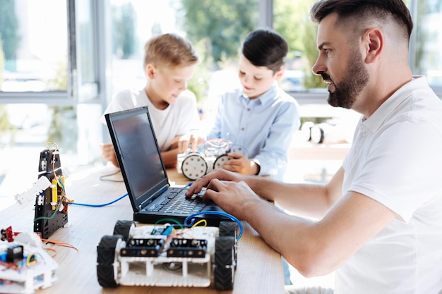 Adorabili bambini pre-adolescenti che ispezionano l'officina del veicolo robotico