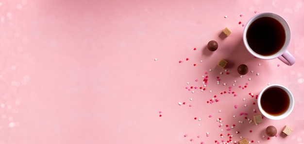 Adoro le bevande. Tazze da tè, caramelle dolci al cioccolato su sfondo rosa cuori. San Valentino 14 febbraio concetto minimo. Banner largo