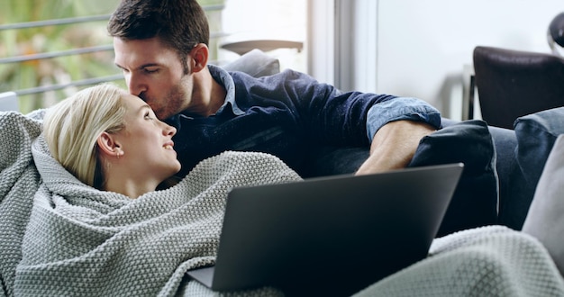 Adoro questi tipi di giorni con te Ritagliata di un bel giovane che bacia la sua ragazza sulla fronte mentre è sdraiato sul divano di casa